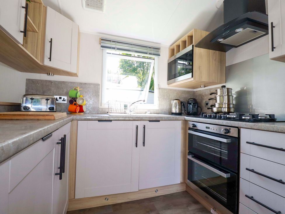 A kitchen with a sink, oven, and various appliances at Meadow 46 in Newquay