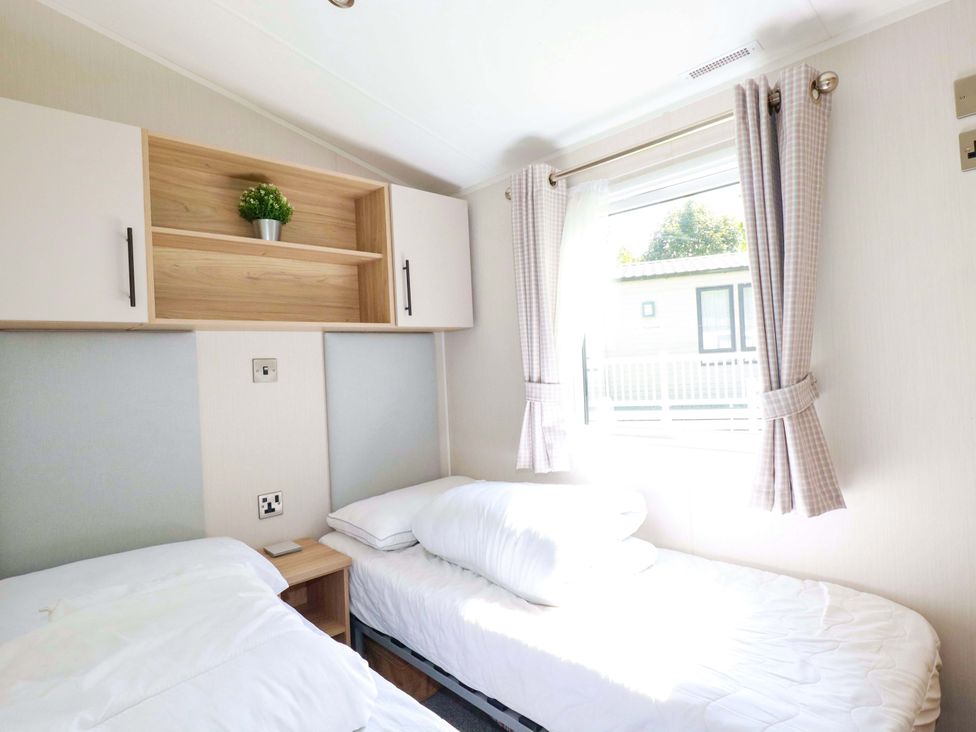 A bedroom with two beds and a shelf at Meadow 46 in Newquay