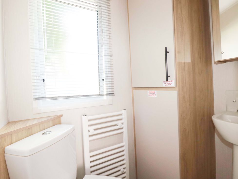 A bathroom with a toilet, hand basin, and storage cabinet at Meadow 46 in Newquay