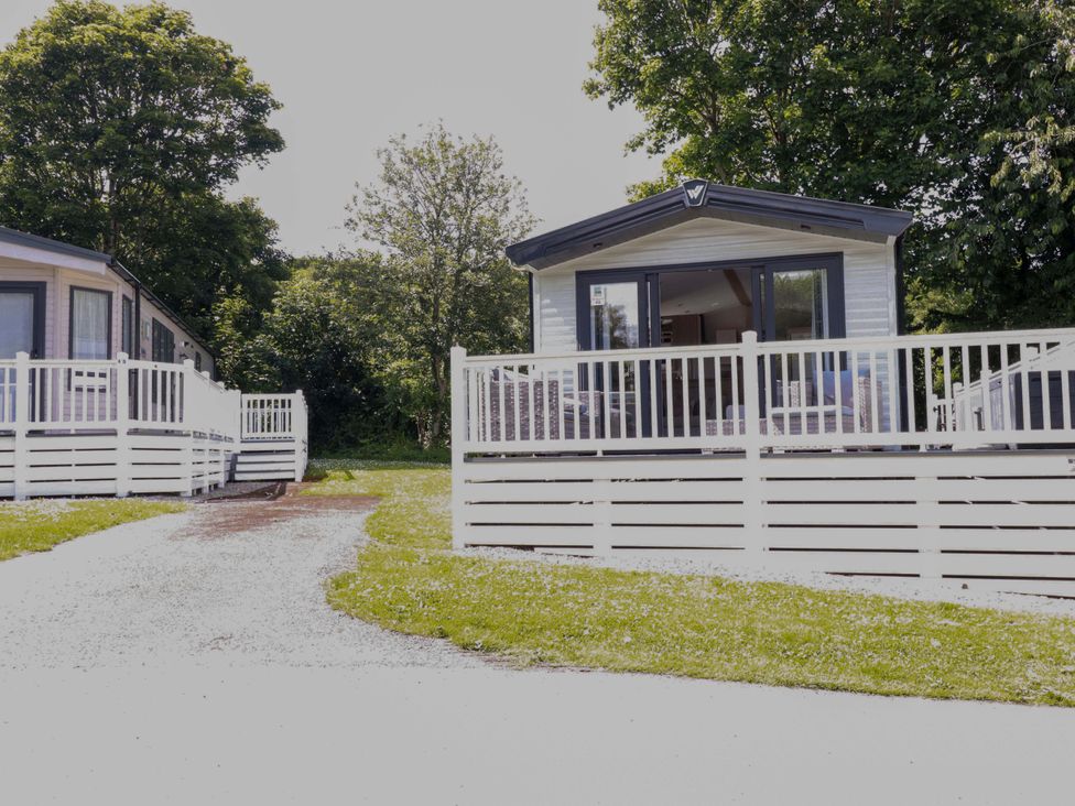 Two mobile homes with decks and a road at Meadow 46 in Newquay