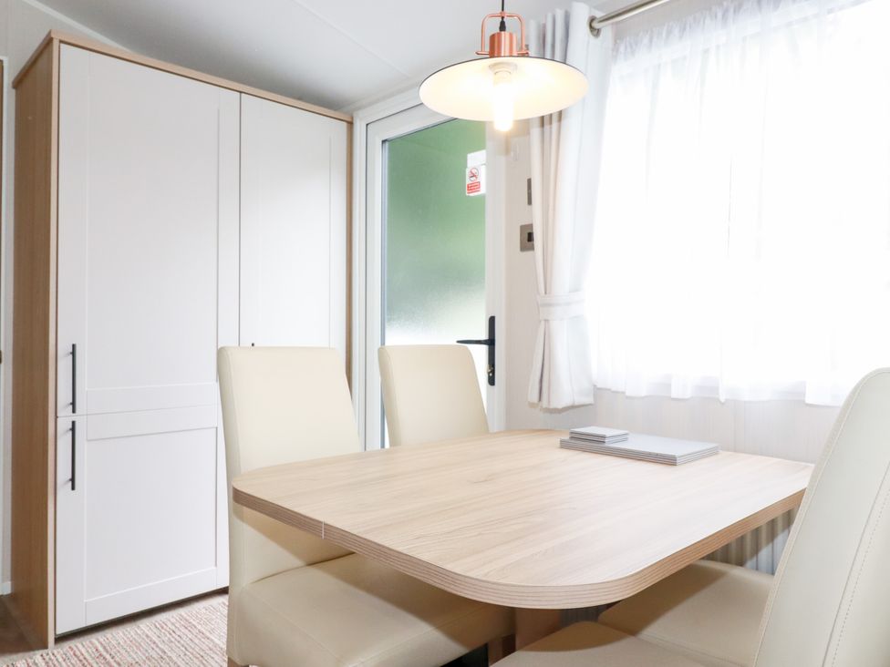 A dining room with a wooden table and chairs at Meadow 46 in Crantock