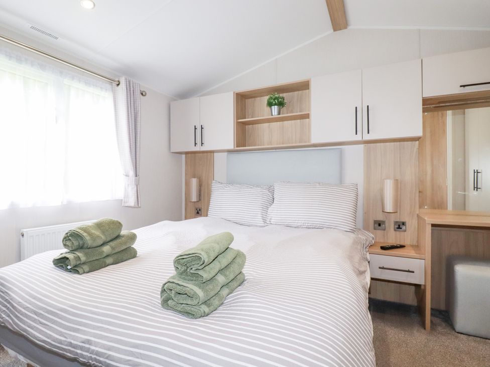 A bedroom with a bed and folded towels at Meadow 46 in Crantock