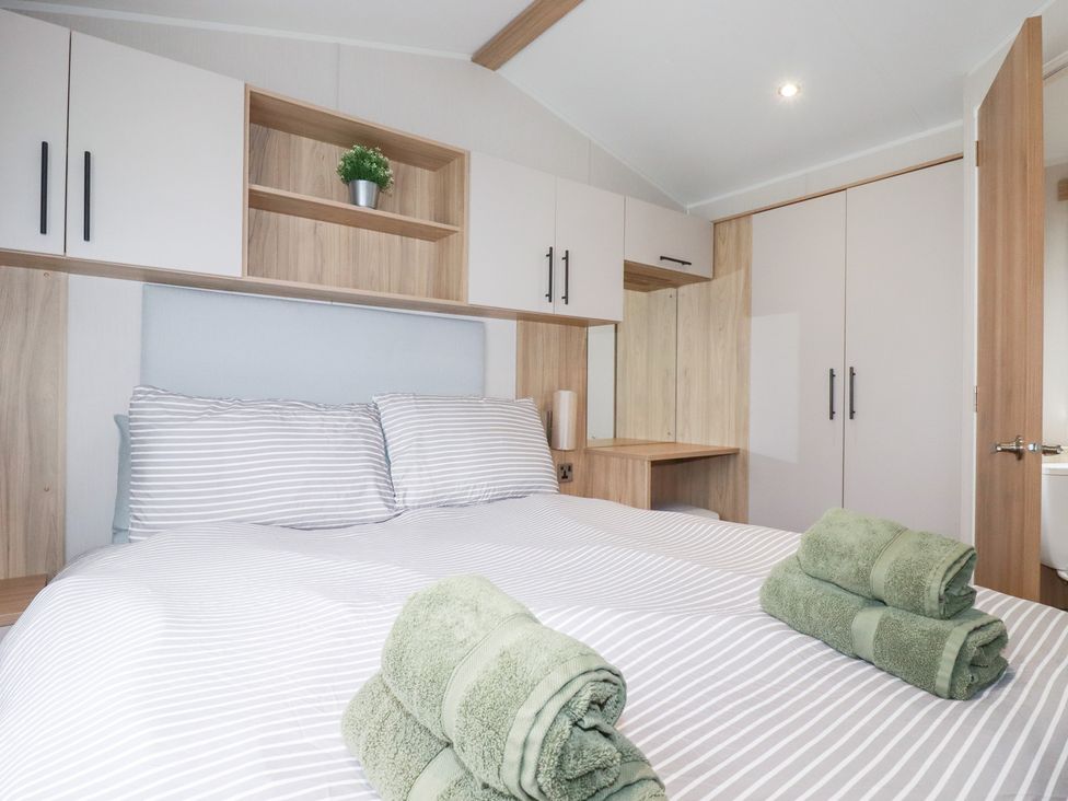 A bedroom with a double bed and towels on the bed at Meadow 46 in Crantock