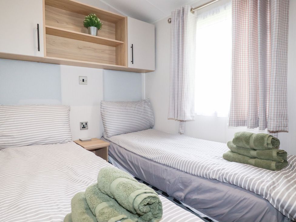 A bedroom with twin beds and a shelf at Meadow 46 in Crantock