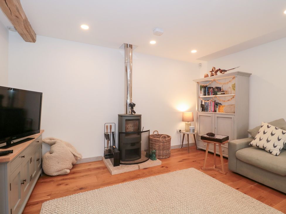 A living room with a stove and television at The Threshing Barn in Chipping Norton