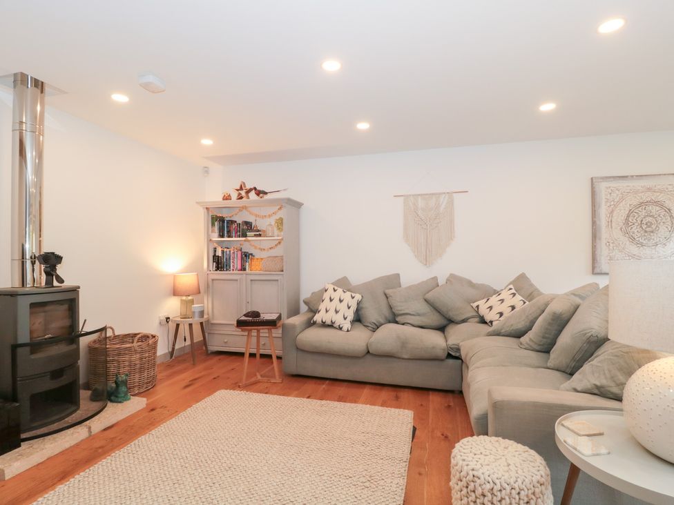 A living room with a sofa, fireplace, and bookshelf at The Threshing Barn in Chipping Norton