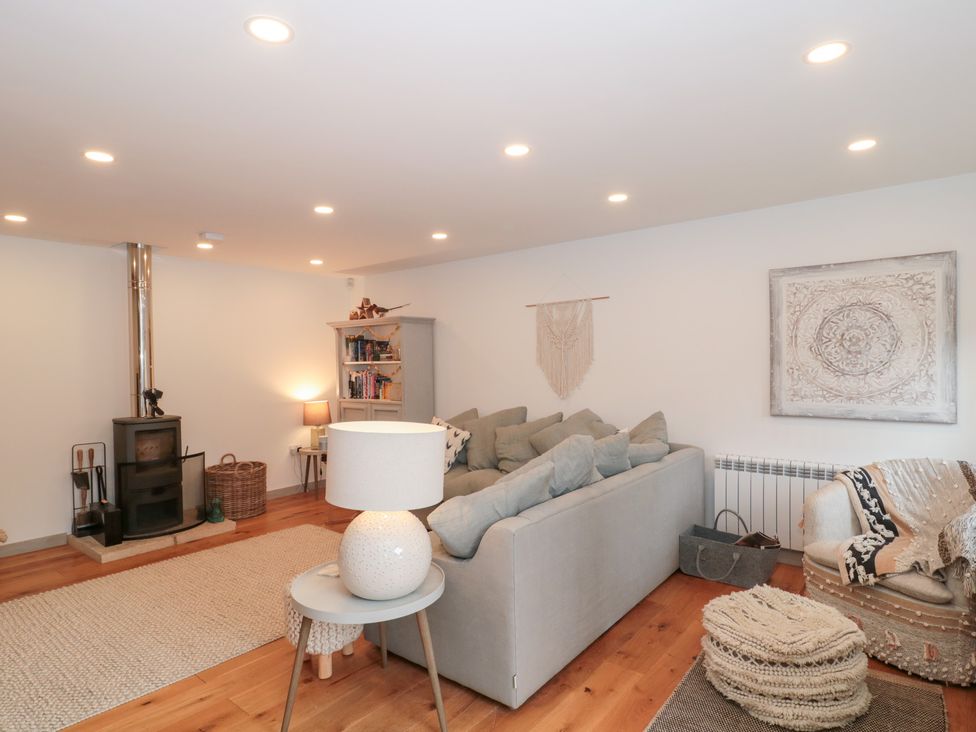 A living room with a sofa, fireplace, and bookshelf at The Threshing Barn in Chipping Norton
