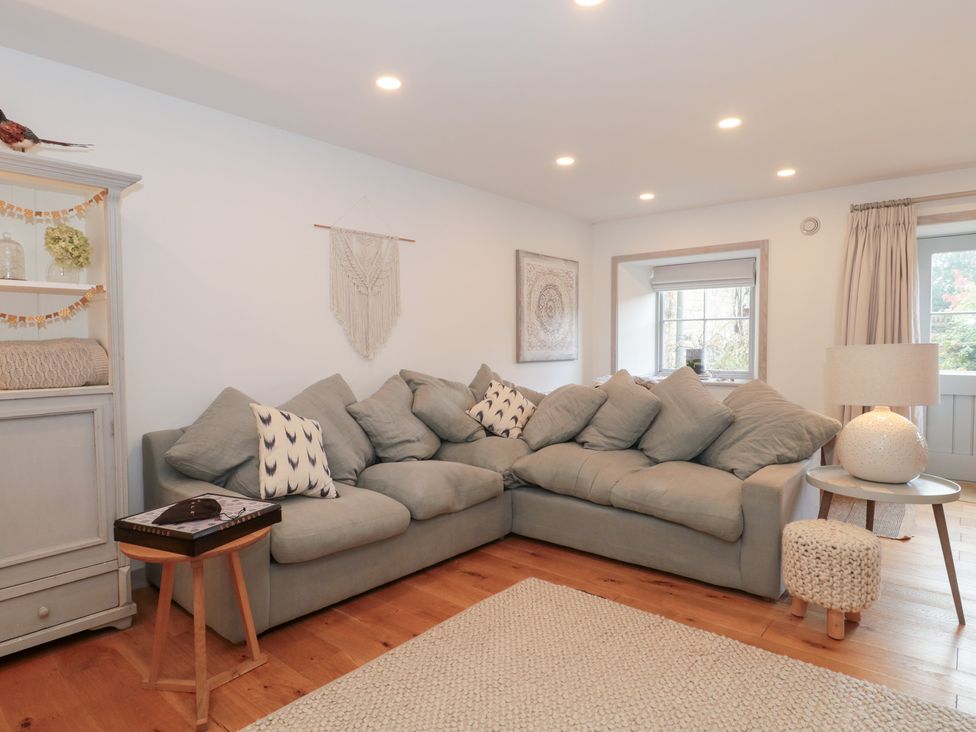 A living room with a sofa, side table and lamp at The Threshing Barn in Chipping Norton