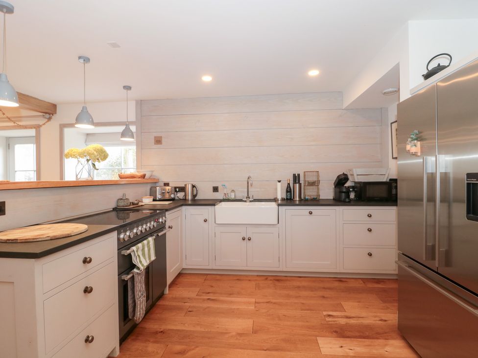 A kitchen with white cabinets and stainless steel appliances at The Threshing Barn in Chipping Norton