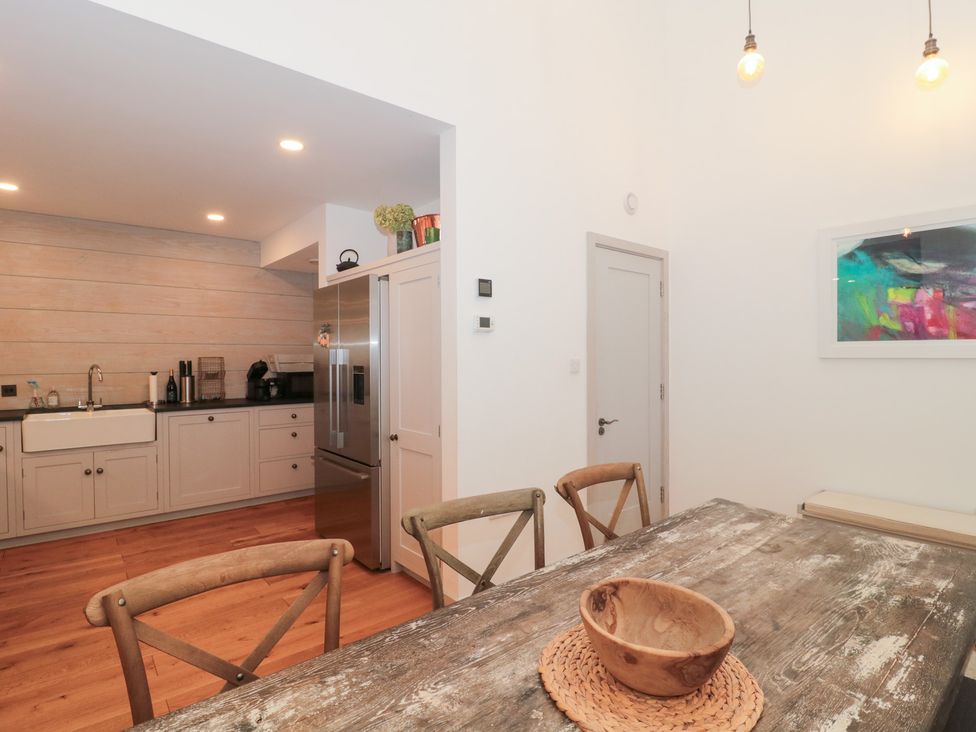 A kitchen with dining table and refrigerator at The Threshing Barn in Chipping Norton