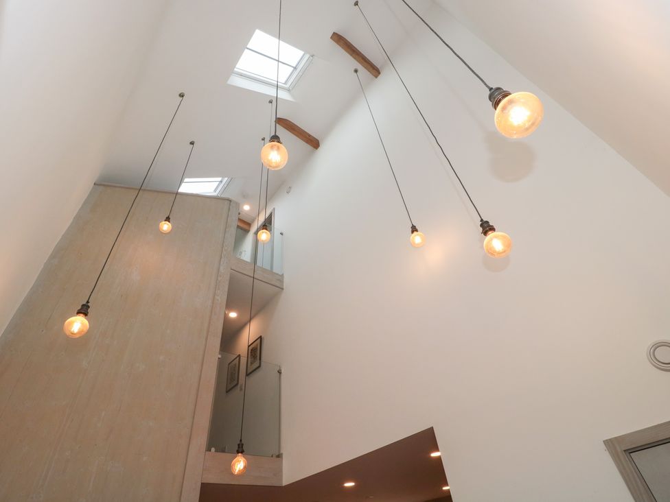 A hallway with hanging light fixtures and skylights at The Threshing Barn in Chipping Norton