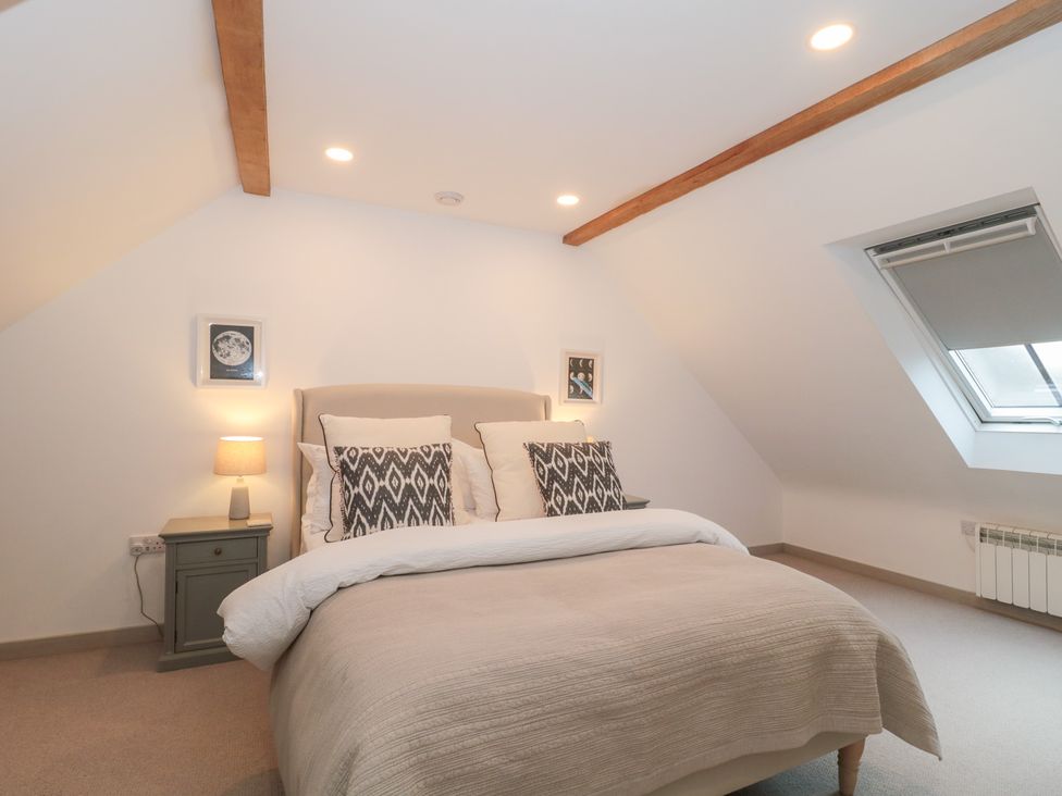A bedroom with a bed and bedside lamp at The Threshing Barn Chipping Norton
