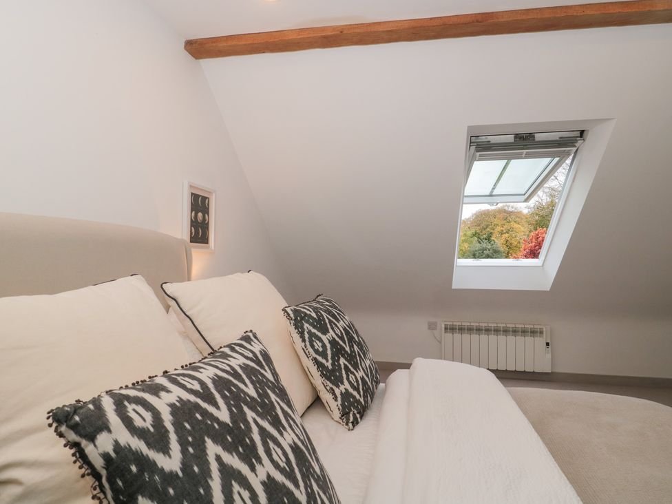 A bedroom with a bed and window at The Threshing Barn in Chipping Norton