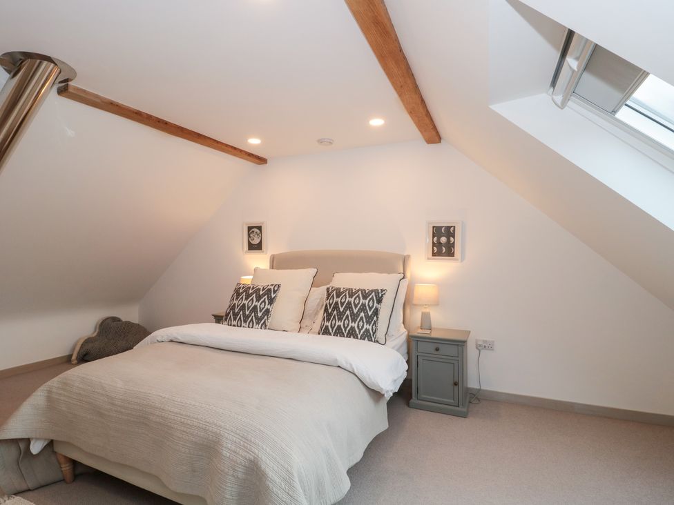 A bedroom with a bed and a nightstand at The Threshing Barn in Chipping Norton