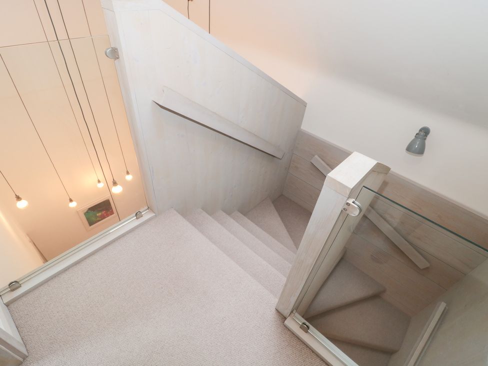 A staircase with a handrail and glass panel at The Threshing Barn in Chipping Norton