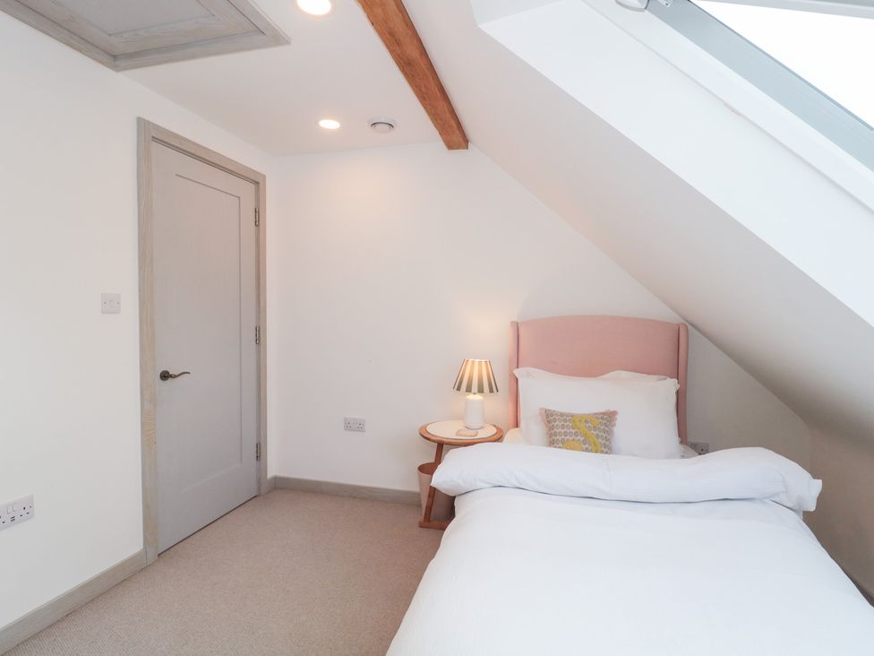 A bedroom with a bed and bedside table at The Threshing Barn in Chipping Norton