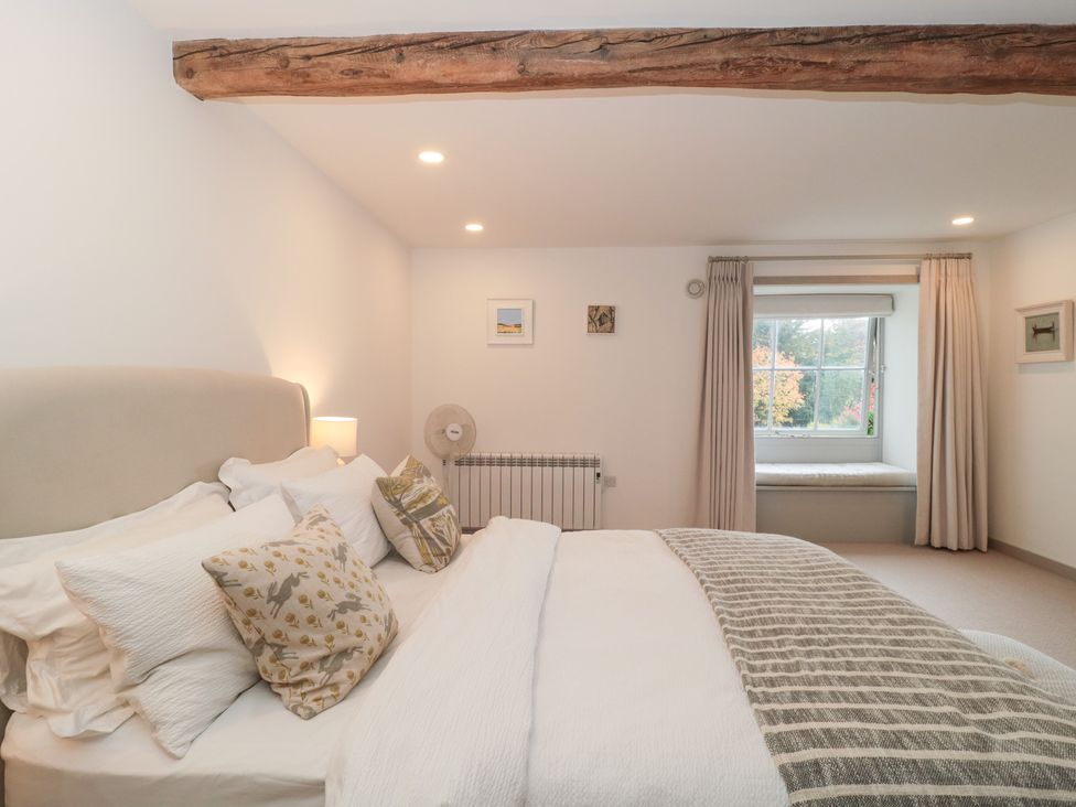 A bedroom with a bed and window at The Threshing Barn in Chipping Norton