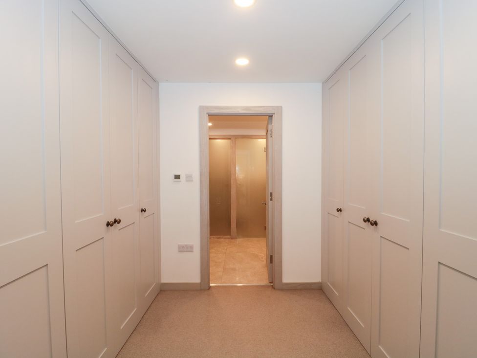 A hallway with wardrobes and a door leading to another room at The Threshing Barn in Chipping Norton