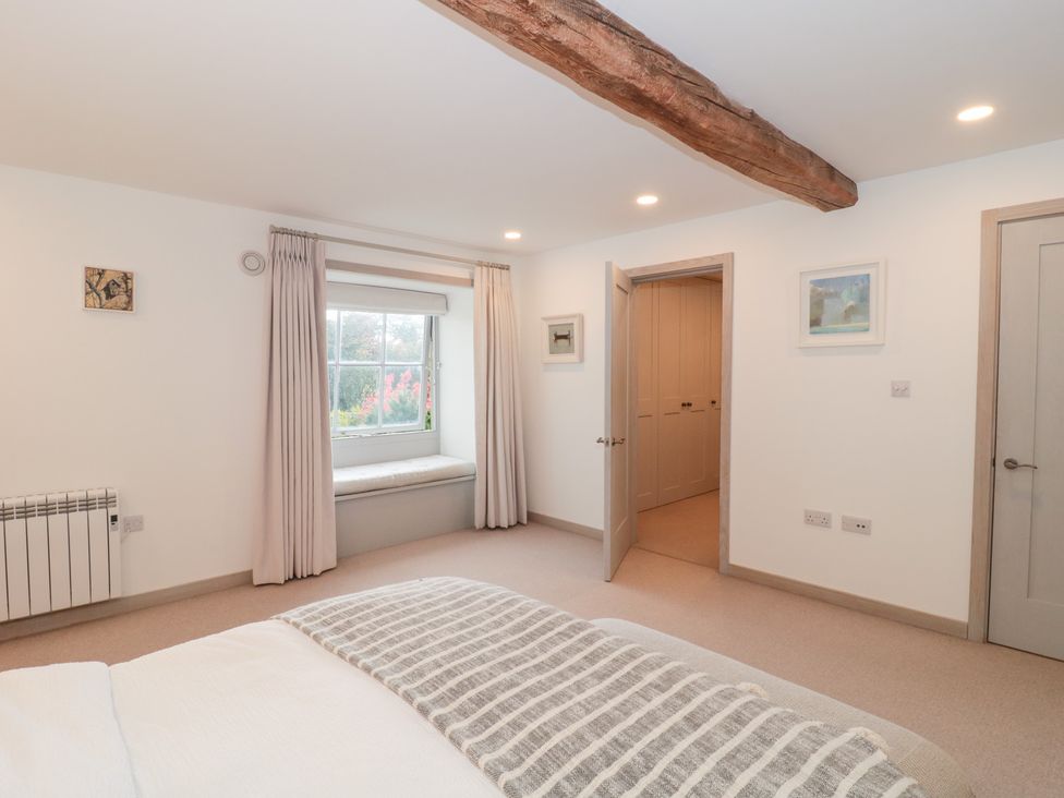 A bedroom with a window and door at The Threshing Barn in Chipping Norton