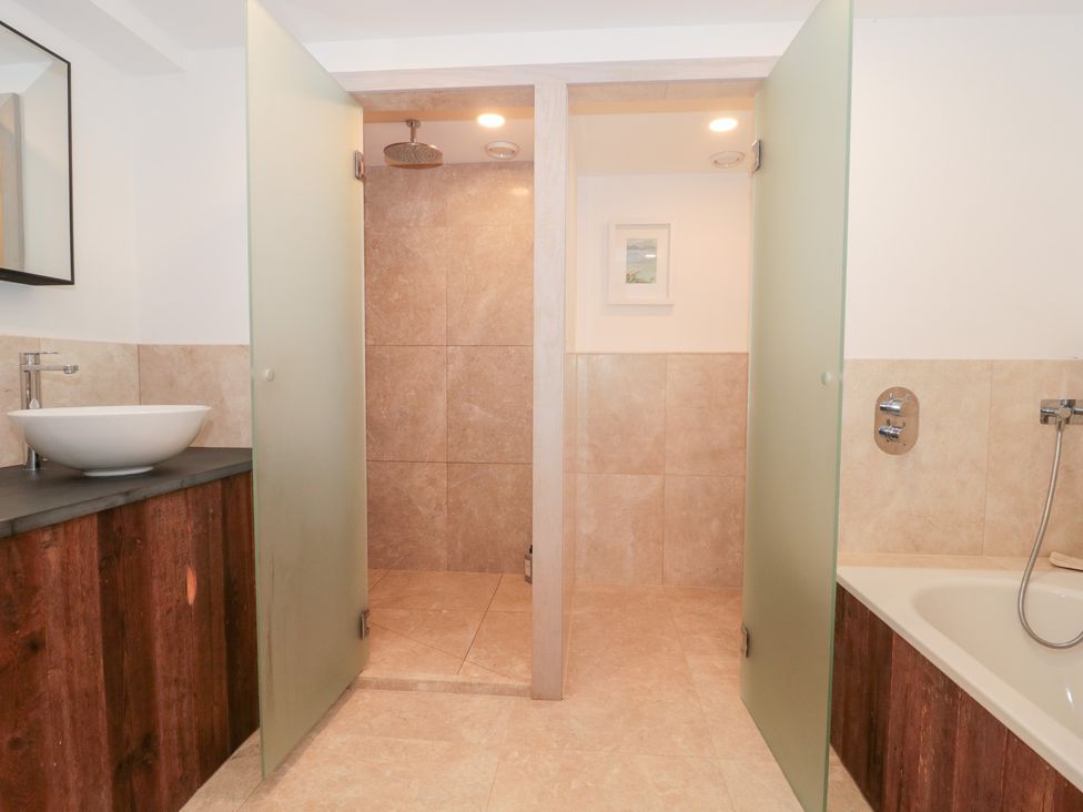 A bathroom with a shower and bathtub at The Threshing Barn in Chipping Norton