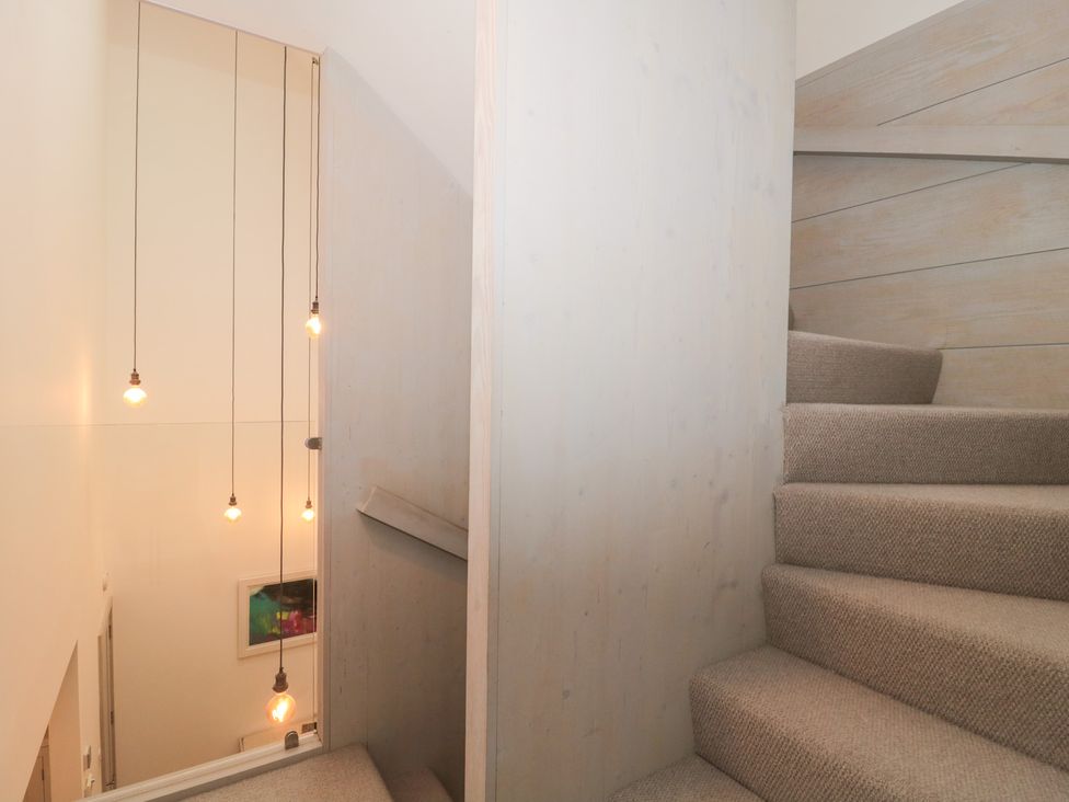 A staircase with lights hanging above at The Threshing Barn in Chipping Norton