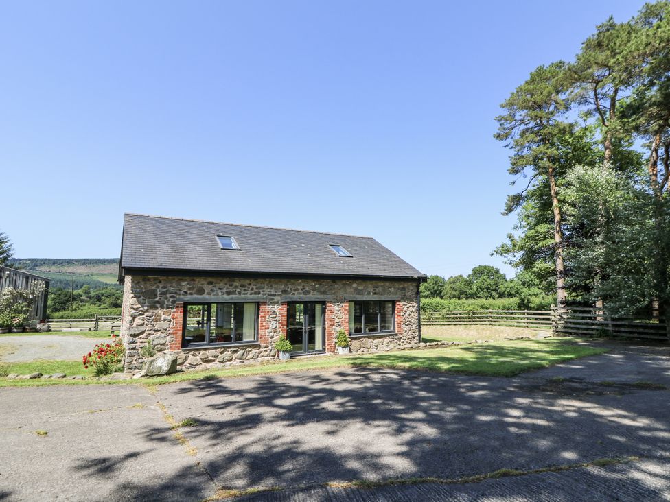 A stone barn with a gray roof and driveway at Little Penrhosgoch Barn in Llandrindod Wells