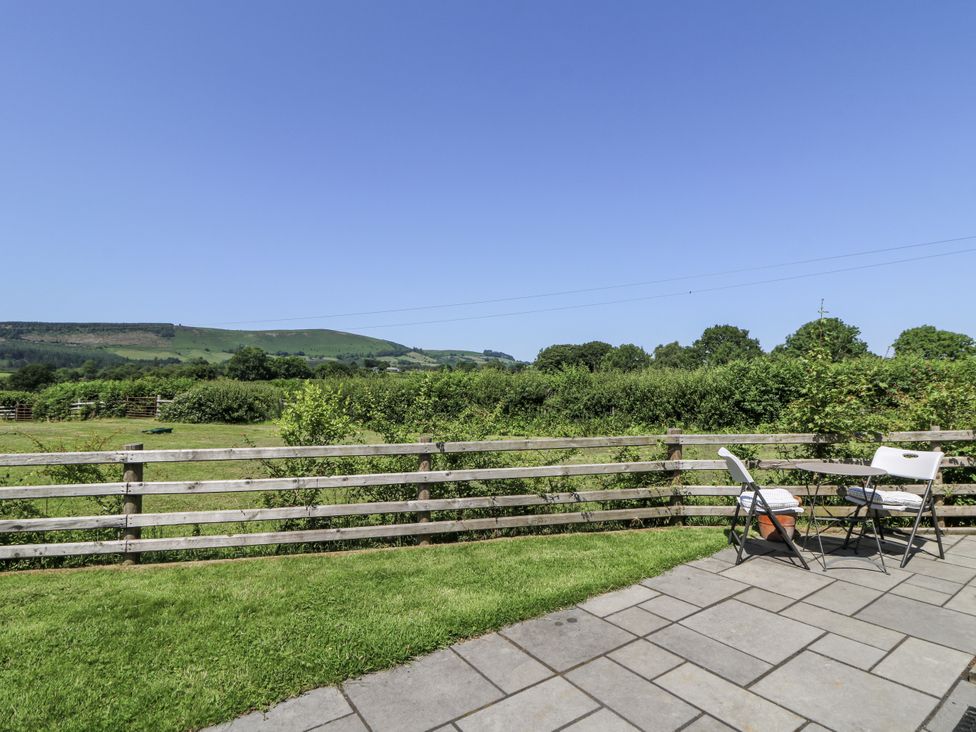 A patio area with chairs and table overlooking fields at Little Penrhosgoch Barn in Llandrindod Wells