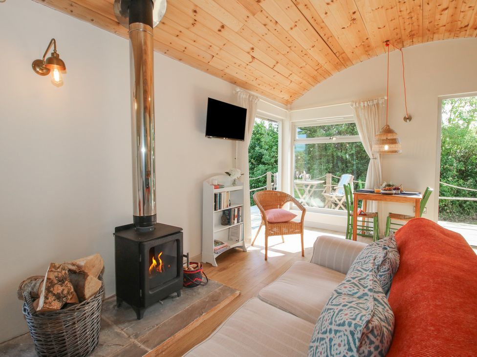A living room with a wood stove and a dining area at Squirrel's Drey Chapel Lawn near Clun