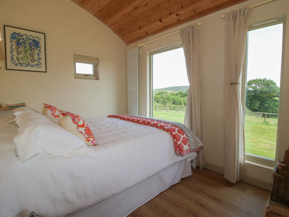 A bedroom with a bed and windows at Owl's Hollow in Chapel Lawn near Clun