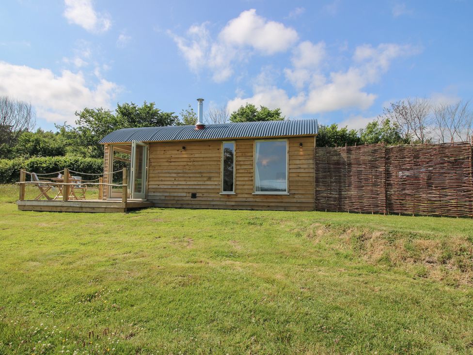 A wooden cabin with a deck in a grassy area at Owl's Hollow Chapel Lawn near Clun