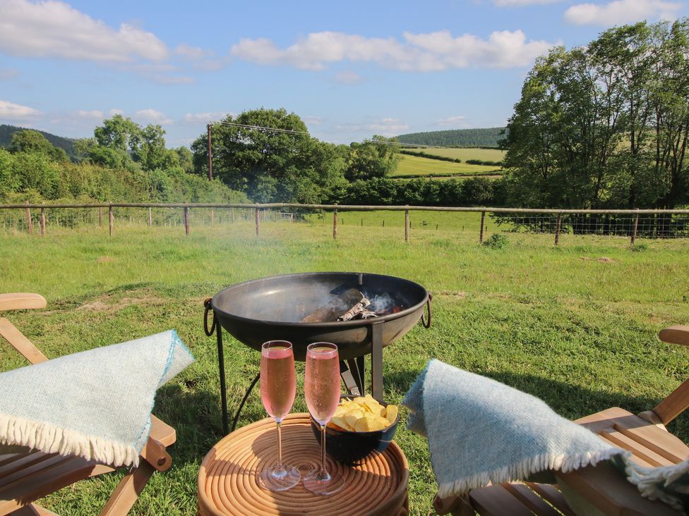 A fire pit with drinks and snacks in a field at Owl's Hollow in Chapel Lawn near Clun