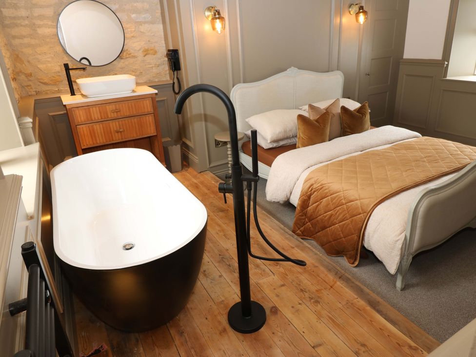 A bedroom with a bathtub, sink, and bed at White House in Durham
