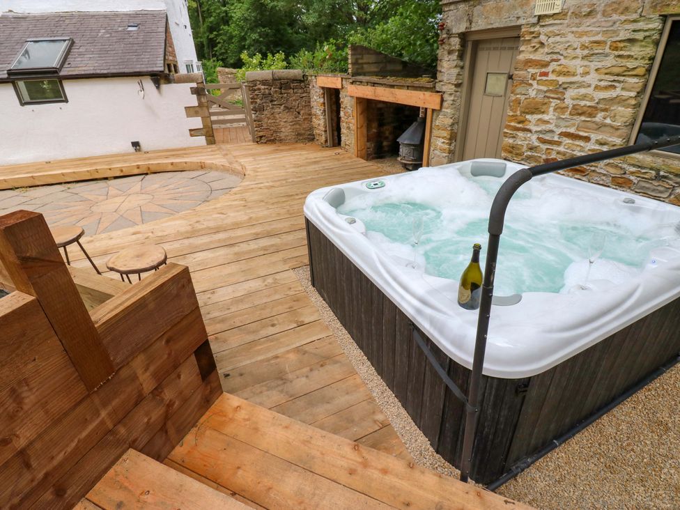 An outdoor area with a hot tub and wooden deck at White House in Durham