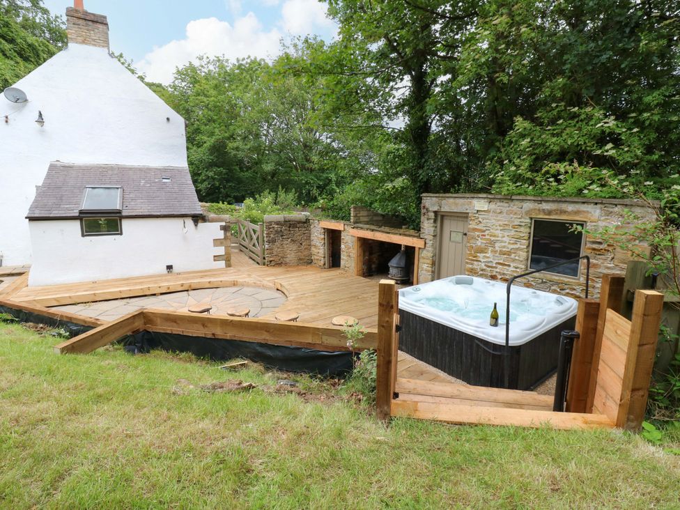 An outdoor area with a hot tub and wooden deck at White House in Durham