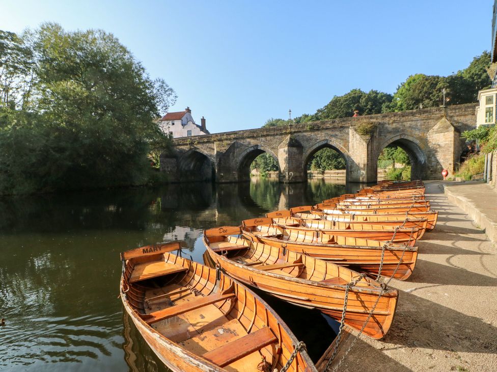 A row of wooden boats tied along the river at White House in Durham