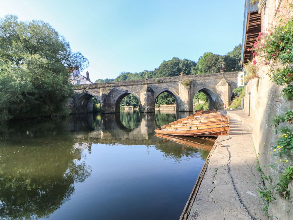 A bridge over water with boats lined up at The Old Barn in Durham