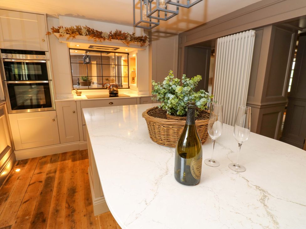 A kitchen with a wine bottle and glasses on the island at White House in Durham