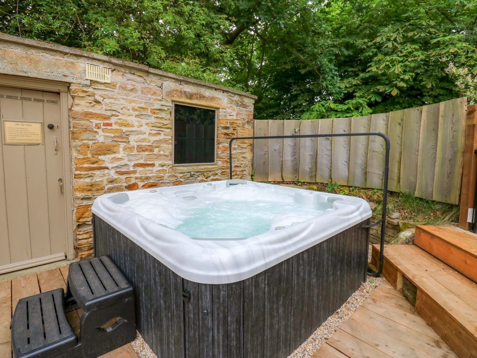 A hot tub next to a stone wall in an outdoor area at White House in Durham