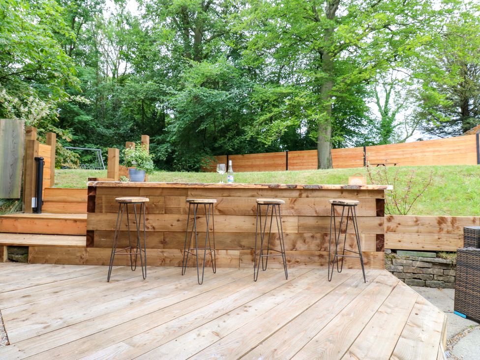 A bar with stools on a wooden deck surrounded by trees at White House in Durham