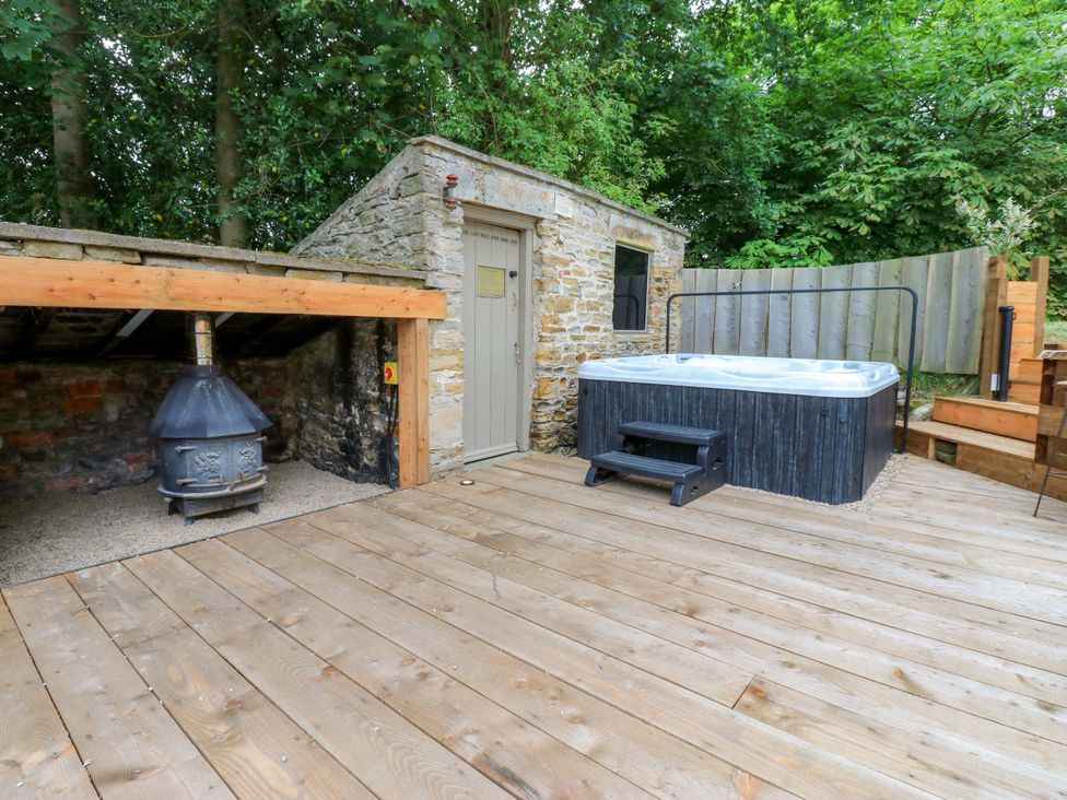 An outdoor area with a hot tub and a stone building at White House in Durham