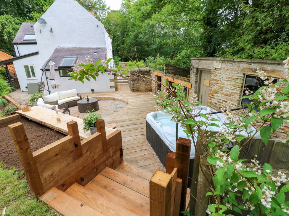 An outdoor area with a deck, seating, and a hot tub at White House in Durham