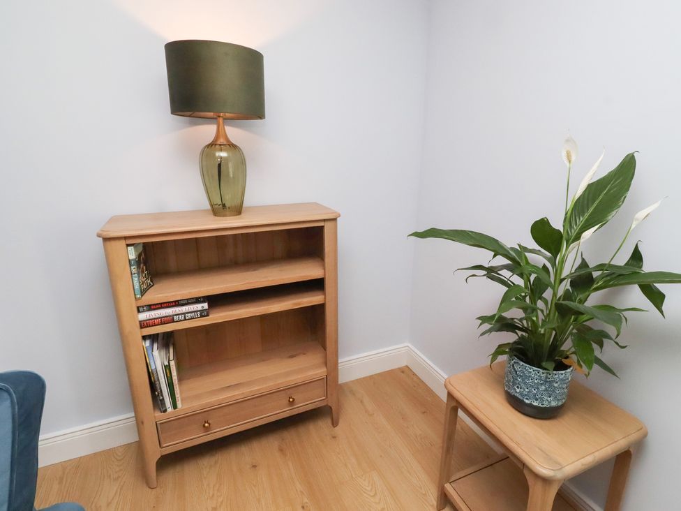 A living room with a bookshelf and a lamp at Linn Cottage in Hexham