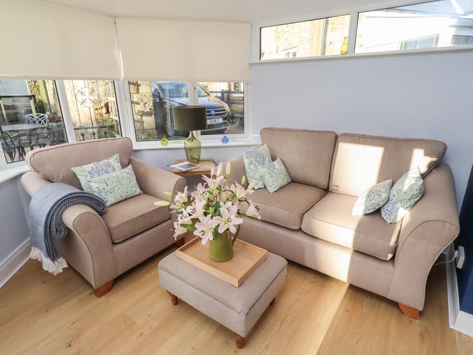 A living room with a sofa and flowers on a coffee table at Linn Cottage in Hexham