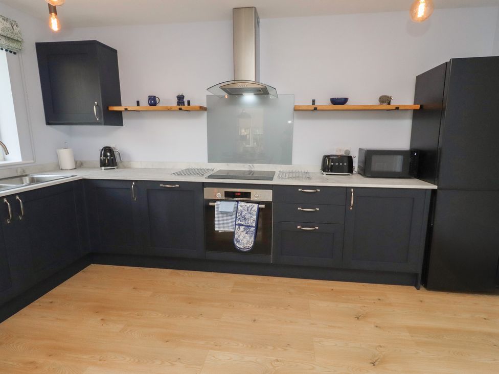 A kitchen with dark cabinets and appliances at Linn Cottage Hexham