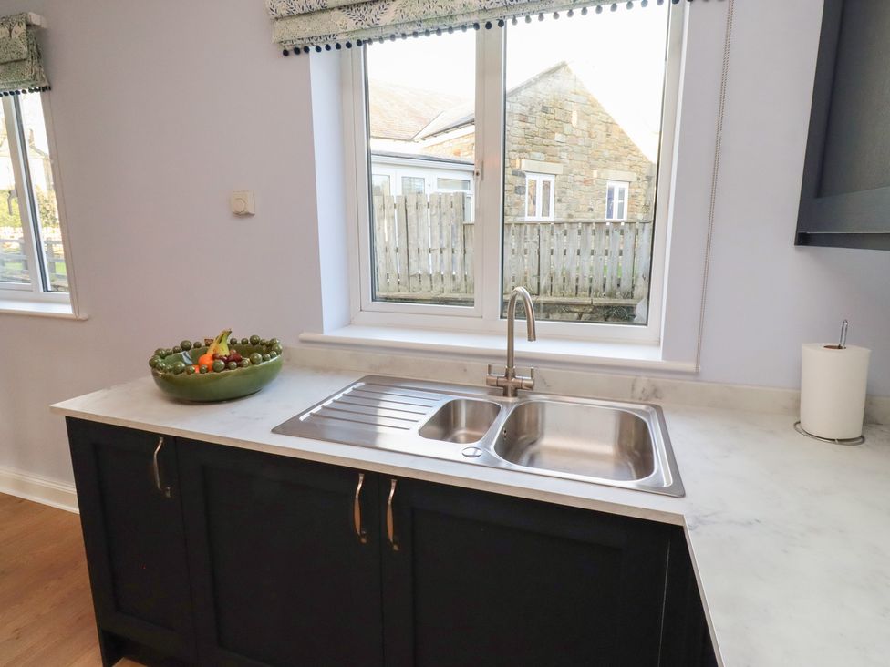 A kitchen with a sink and a bowl of fruit at Linn Cottage in Hexham
