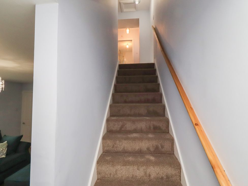 A staircase with carpet and a handrail at Linn Cottage in Hexham