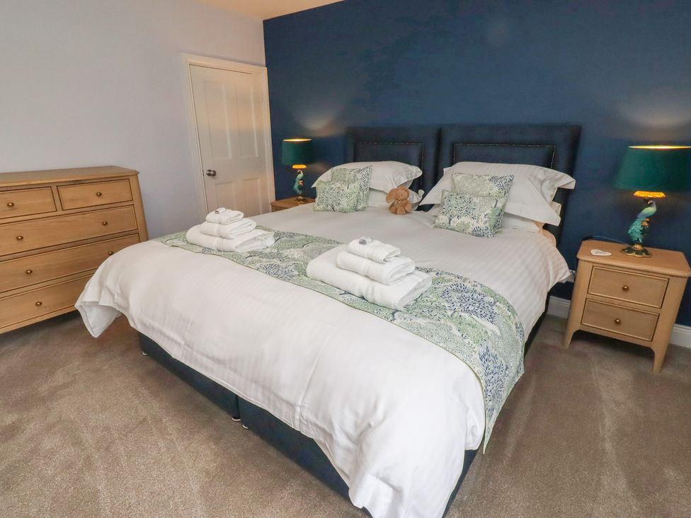 A bedroom with a bed and nightstands at Linn Cottage Hexham