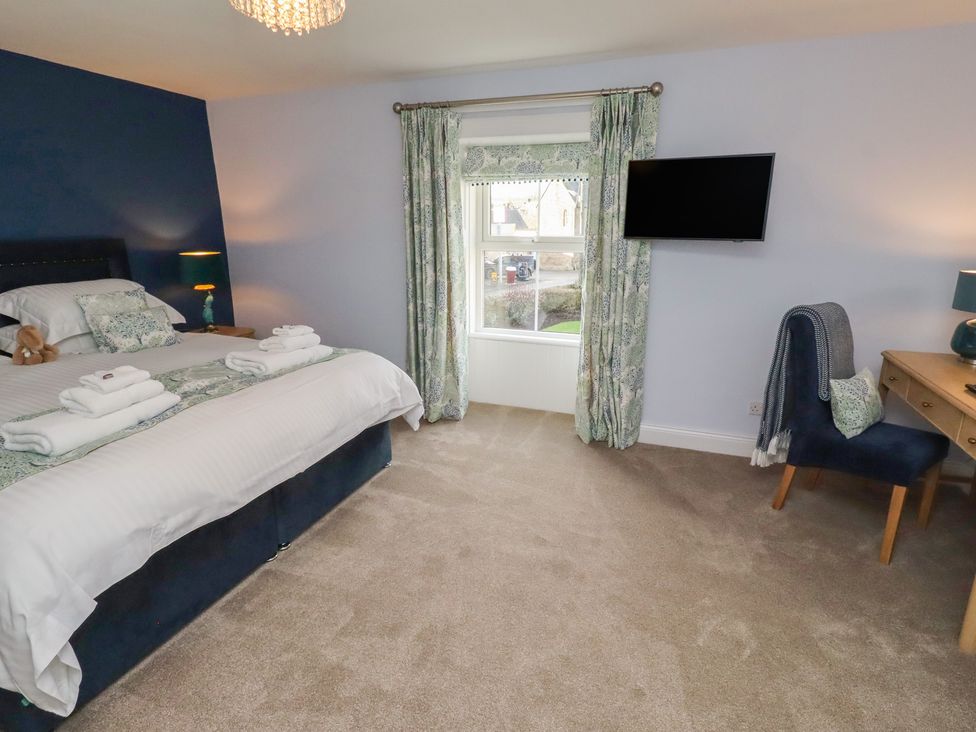 A bedroom with a bed and desk at Linn Cottage in Hexham
