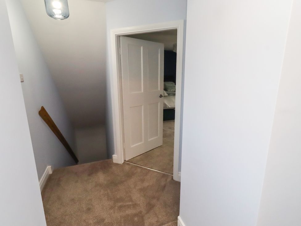 A hallway with a staircase and a door at Linn Cottage in Hexham