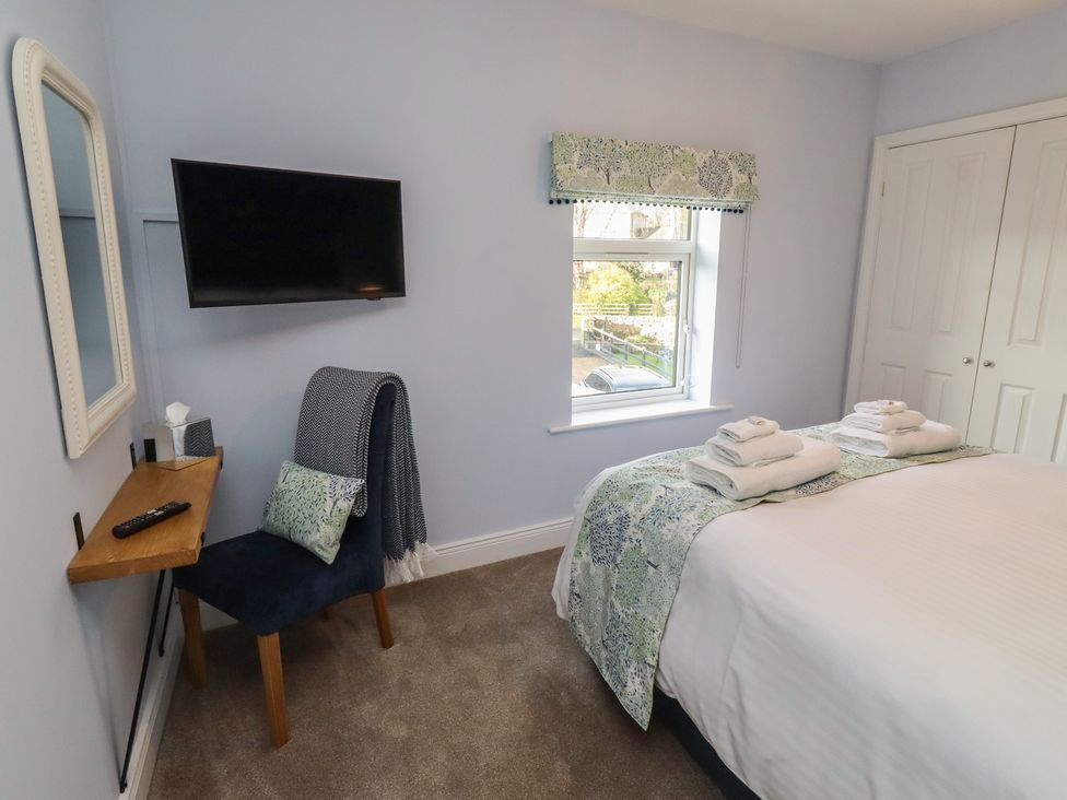 A bedroom with a bed and a television at Linn Cottage in Hexham